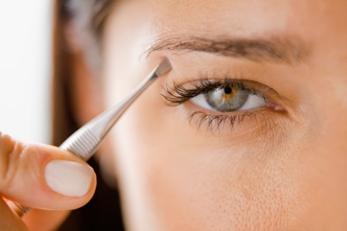 woman plucking eyelashes