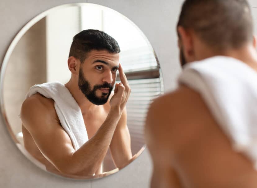 Man looking for eyebrow mites in the mirror